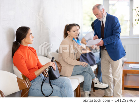 Queue of applicants in reception room, senior male manager talking to office-seeker in background. Queue of applicants in reception room, senior male manager talking to office-seeker in background. 141252466