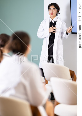 Young female doctor presenting with remote control in meeting room Young female doctor presenting with remote control in meeting room 141252498
