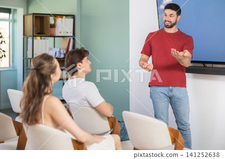 Man with remote controller speaks to audience of listeners Man with remote controller speaks to audience of listeners 141252638