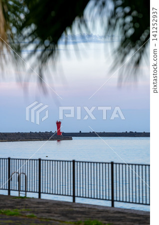 A red lighthouse standing in the evening sky A red lighthouse standing in the evening sky 141252937