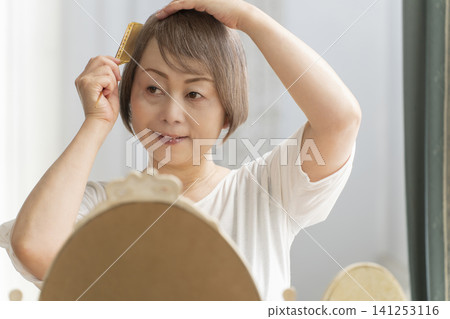 一位老婦人正在用梳子梳理頭髮。 一位老婦人正在用梳子梳理頭髮。 141253116