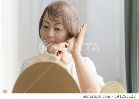 一位老婦人正在用梳子梳理頭髮。 一位老婦人正在用梳子梳理頭髮。 141253128