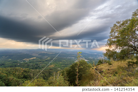 A mountain range covered in the wild woods illuminated by the golden light of the setting sun. A natural Park reserve or hunting grounds. Recreational outdoor tourism A mountain range covered in the wild woods illuminated by the golden light of the setting sun. A natural Park reserve or hunting grounds. Recreational outdoor tourism 141254354