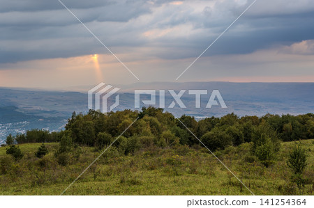 A mountain range covered in the wild woods illuminated by the golden light of the setting sun. A natural Park reserve or hunting grounds. Recreational outdoor tourism A mountain range covered in the wild woods illuminated by the golden light of the setting sun. A natural Park reserve or hunting grounds. Recreational outdoor tourism 141254364