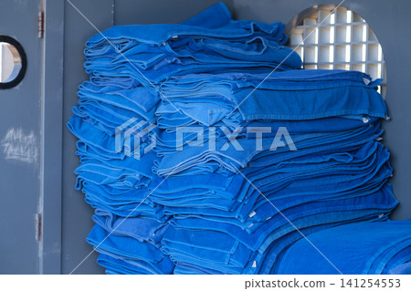 Neatly arranged stack of blue towels stored inside a storage unit, featuring a circular opening in the background for ventilation Neatly arranged stack of blue towels stored inside a storage unit, featuring a circular opening in the background for ventilation 141254553