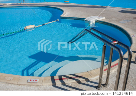 Swimming pool features clear blue water, stainless steel handrails, and a depth marker indicating 90 cm on the pool edge Swimming pool features clear blue water, stainless steel handrails, and a depth marker indicating 90 cm on the pool edge 141254614