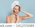 Woman with mask on face, towel on head, smiling joyfully 141255089