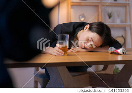 一個穿著西裝的女人喝啤酒喝醉了。 一個穿著西裝的女人喝啤酒喝醉了。 141255203