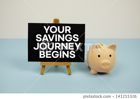 Your Savings Journey Begins text written on paper card with easel and piggy bank 141255326