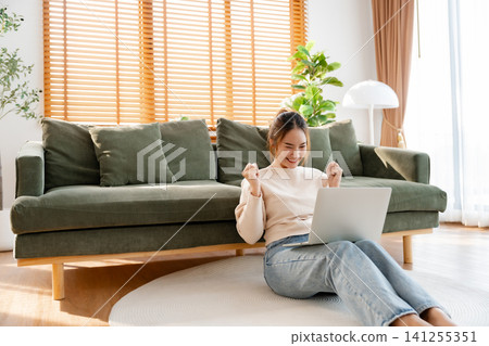 Funny euphoric young asian woman celebrating winning Funny euphoric young asian woman celebrating winning 141255351