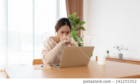 Asian woman are stressed, pain in their eyes, working on laptop in living room at home Asian woman are stressed, pain in their eyes, working on laptop in living room at home 141255352