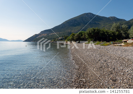 Empty pebble beach next to the calm blue sea. Empty pebble beach next to the calm blue sea. 141255781