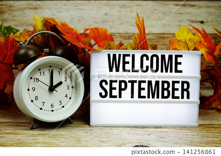 Welcome September text with alarm clock and maple leaf decoration on wooden background Welcome September text with alarm clock and maple leaf decoration on wooden background 141256861