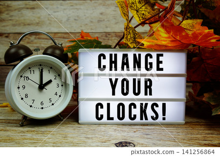 Change Your Clocks! text with alarm clock and maple leaf decoration on wooden background Change Your Clocks! text with alarm clock and maple leaf decoration on wooden background 141256864