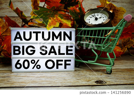 Autumn Big Sale 60% off text with trolley shopping cart and alarm clock decoration with maple leaf on wooden background Autumn Big Sale 60% off text with trolley shopping cart and alarm clock decoration with maple leaf on wooden background 141256890