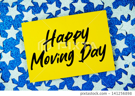 Happy Moving Day text written on paper card with star glitter on blue background Happy Moving Day text written on paper card with star glitter on blue background 141256898