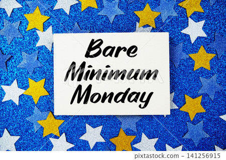 Bare Minimum Monday text written on paper card with star glitter on blue background Bare Minimum Monday text written on paper card with star glitter on blue background 141256915