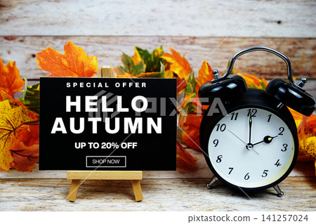 Hello Autumn Sale 20% off Special Offer text with alarm clock and maple leaf decoration on wooden background Hello Autumn Sale 20% off Special Offer text with alarm clock and maple leaf decoration on wooden background 141257024
