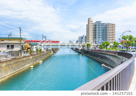 A red Keikyu Line train runs across the Hirasaku River and railway bridge in Kurihama, Yokosuka City, Kanagawa Prefecture. A red Keikyu Line train runs across the Hirasaku River and railway bridge in Kurihama, Yokosuka City, Kanagawa Prefecture. 141257101