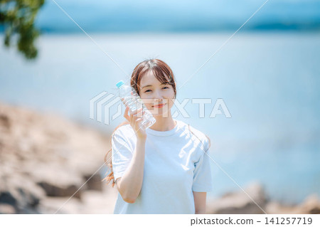 Woman hydrating in the shade of a tree Woman hydrating in the shade of a tree 141257719