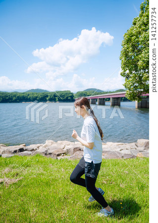 一位女子沿著湖岸奔跑時的側臉 一位女子沿著湖岸奔跑時的側臉 141257734