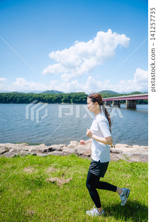 一名女子沿著湖岸奔跑(橫向視角) 一名女子沿著湖岸奔跑(橫向視角) 141257735