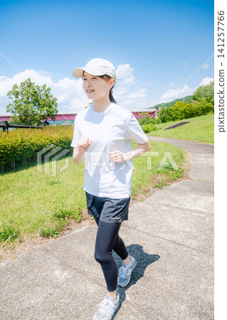 一名女子在海濱大道上奔跑的全身像 一名女子在海濱大道上奔跑的全身像 141257766