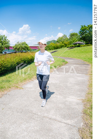 一名女子全身像,在長滿青草的山坡背景下奔跑。 一名女子全身像,在長滿青草的山坡背景下奔跑。 141257767