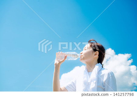 A woman quenches her thirst with bottled water. A woman quenches her thirst with bottled water. 141257798