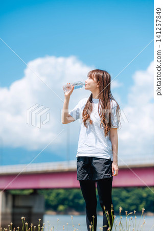 一位女子在河岸邊的野花叢中補充水分。 一位女子在河岸邊的野花叢中補充水分。 141257849