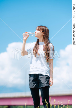 一幅女子全身像,她一邊喝水一邊凝視著藍天。 一幅女子全身像,她一邊喝水一邊凝視著藍天。 141257851