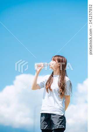 一位女子在藍天下喝水的特寫。 一位女子在藍天下喝水的特寫。 141257852
