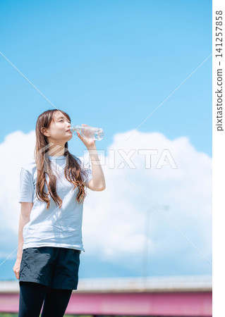 一名女子在藍天下喝下污水-全身照 一名女子在藍天下喝下污水-全身照 141257858