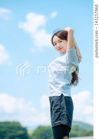 一名女跑步者伸展雙臂。 一名女跑步者伸展雙臂。 141257868