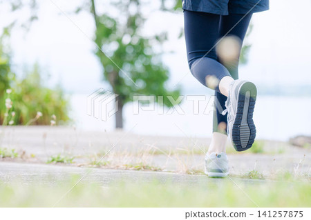 Close-up of a woman's feet as she runs in navy leggings. Close-up of a woman's feet as she runs in navy leggings. 141257875
