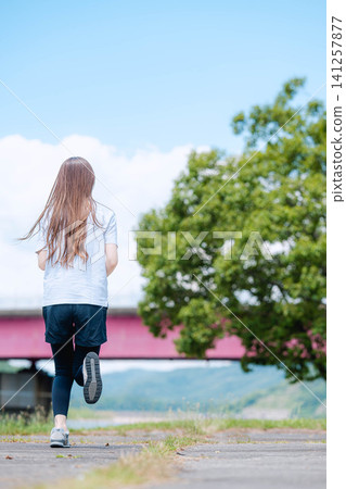 The feet of a woman jogging with a bridge in the background. The feet of a woman jogging with a bridge in the background. 141257877