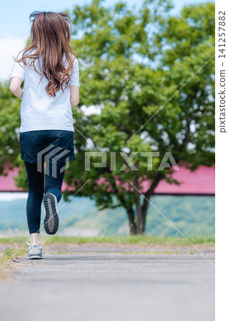 一個長髮女子沿著河岸奔跑。 一個長髮女子沿著河岸奔跑。 141257882