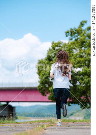 A woman's back as she runs with a mountain range in the background. A woman's back as she runs with a mountain range in the background. 141257893