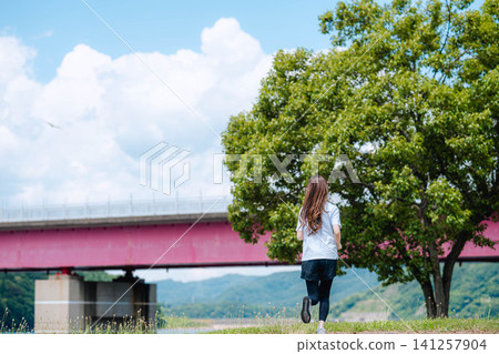 A woman running with mountain ranges and a bridge in the background. A woman running with mountain ranges and a bridge in the background. 141257904