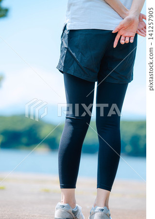 Close-up of a woman's legs standing with a lake in the background. Close-up of a woman's legs standing with a lake in the background. 141257905