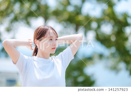 一位女士正在整理散落的頭髮,鏡頭從側面拍攝。 一位女士正在整理散落的頭髮,鏡頭從側面拍攝。 141257923