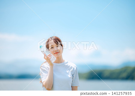 Close-up of a woman smiling while drinking water Close-up of a woman smiling while drinking water 141257935