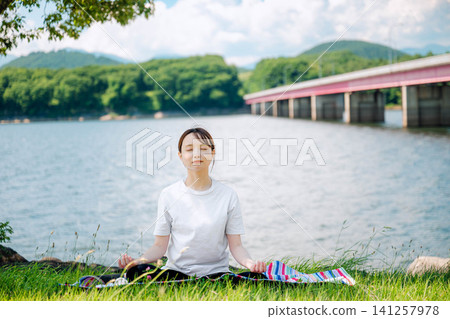 一位女子正在冥想，背景是一座橋。 141257978