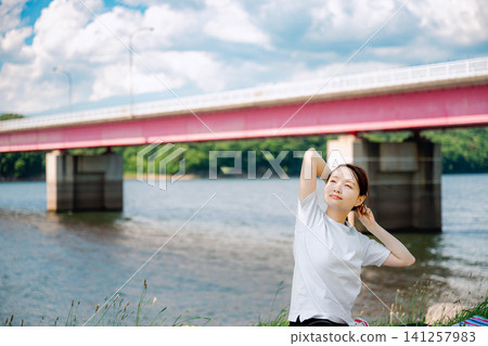 A woman adjusts her hair with a refreshing smile. A woman adjusts her hair with a refreshing smile. 141257983