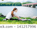 一位綁著馬尾辮的女子正在做前屈伸展運動，背景中可以看到一個橋式。 141257996