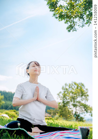 A woman looks up at the sky and clasps her hands together in prayer. A woman looks up at the sky and clasps her hands together in prayer. 141258009