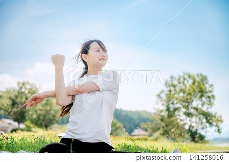 A woman with her hair blowing in the wind stretches out her arms. 141258016