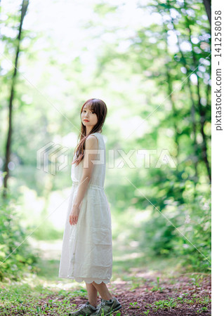 森林裡，一位身穿白裙的女子轉身，露出幸福的笑容。 141258058