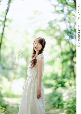 一位身穿白色洋裝的女子轉過身來，臉上帶著燦爛的笑容。 141258059