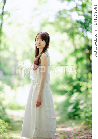 A woman in a white dress stands naturally. 141258061